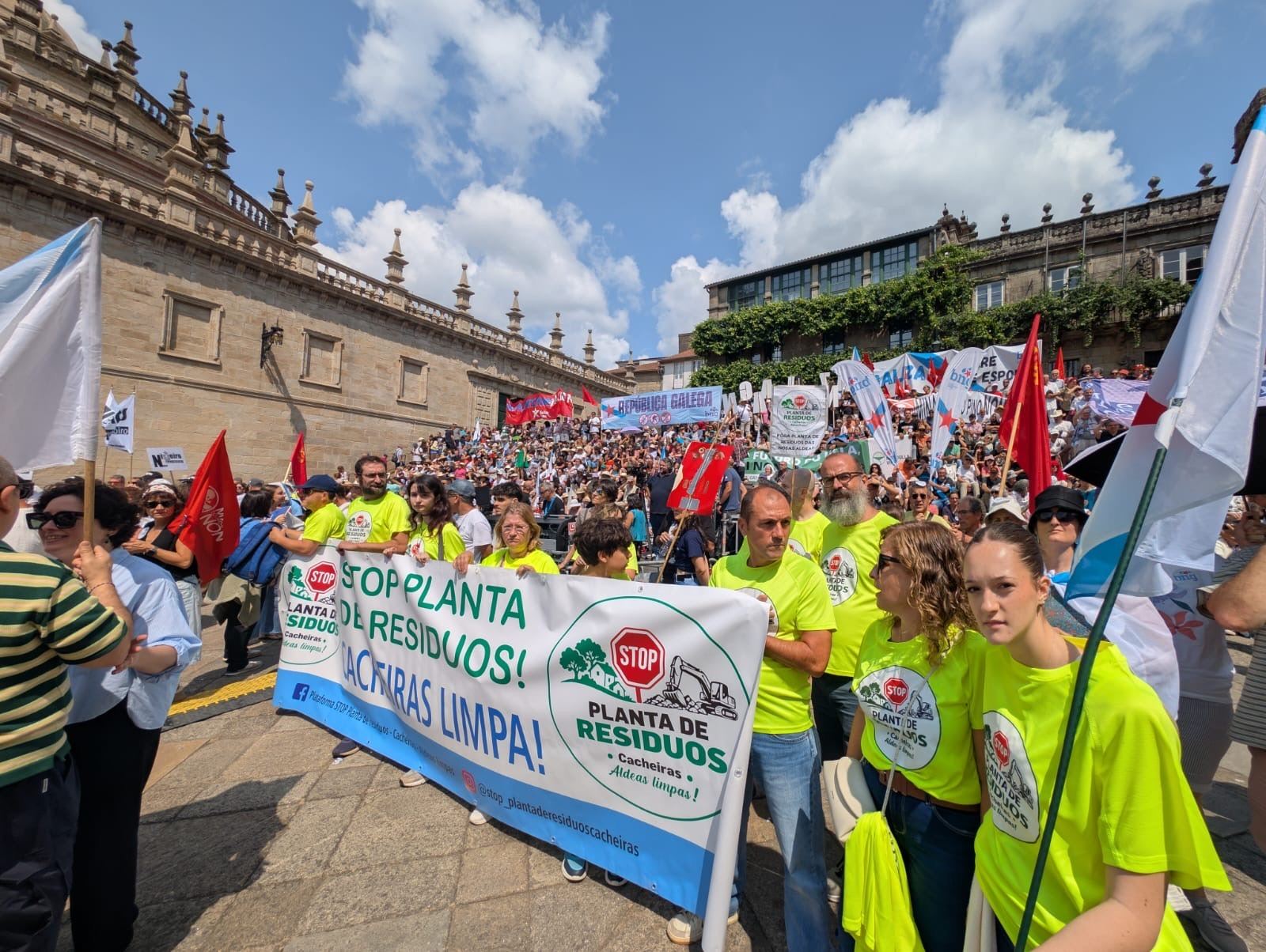 Membros da plataforma coa pancarta nunha praza de Santiago chea de xente e bandeiras.